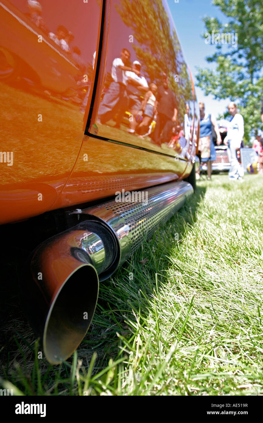 Large exhaust pipe mounted on side of bright orange car at vintage car show Stock Photo