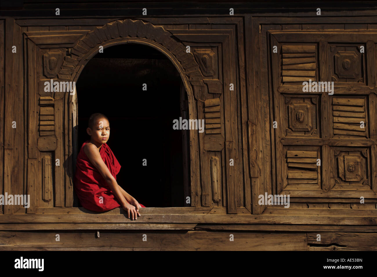 Novice monk sitting in window of 18thC wooden monastery of Nat Taung Kyaung (May-taung taik), Bagan (Pagan), Myanmar (Burma) Stock Photo