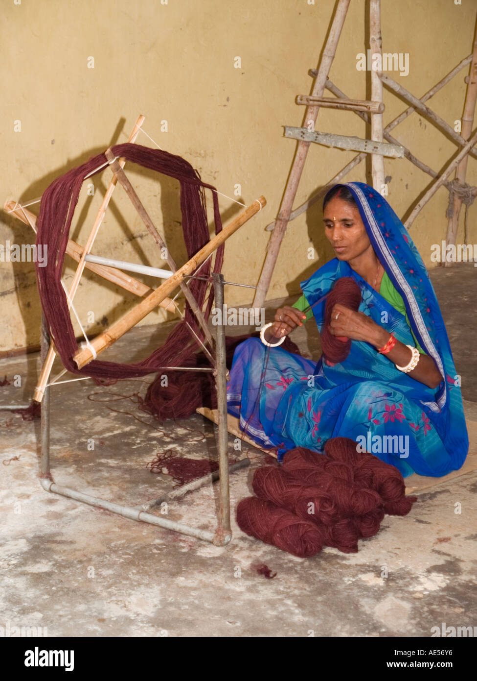 Demonstration of spinning wool with Asian lady in traditional dress sat on floor Stock Photo