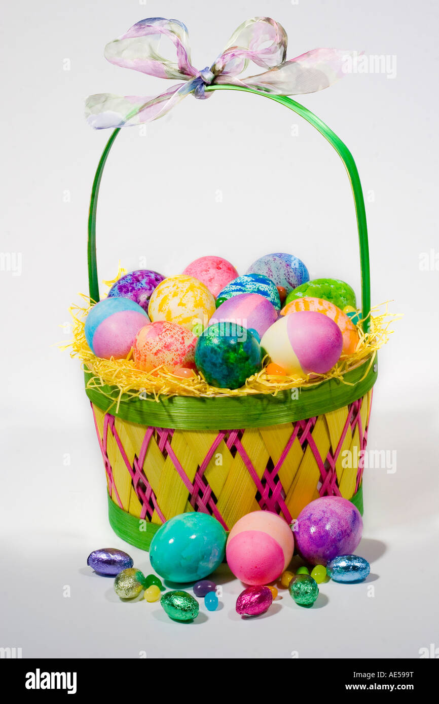 Straw Easter basket filled with colored eggs and candies Stock Photo