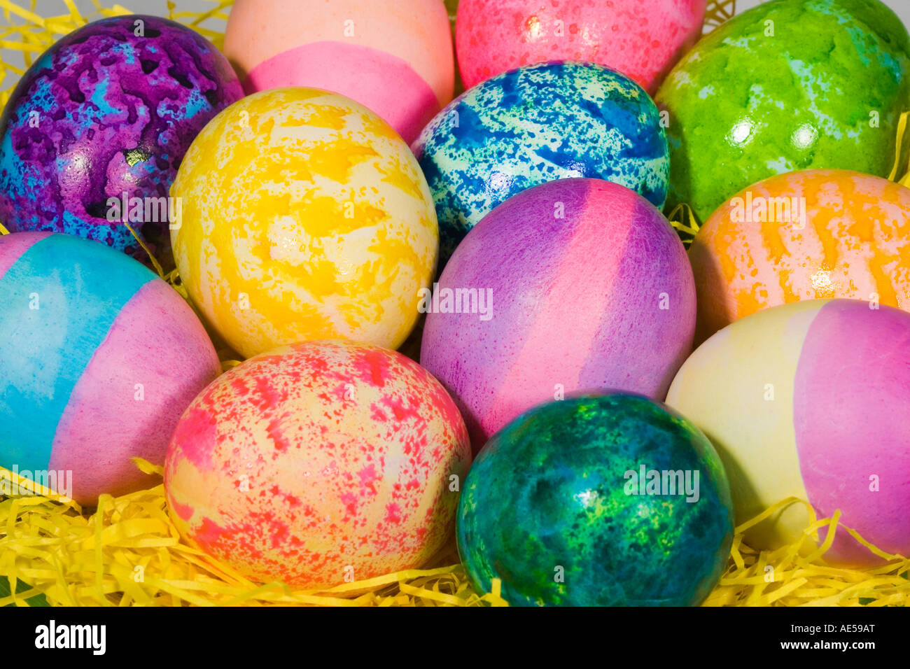 Closeup of a straw Easter basket filled with a dozen coloured eggs of bright colors and patterns Stock Photo