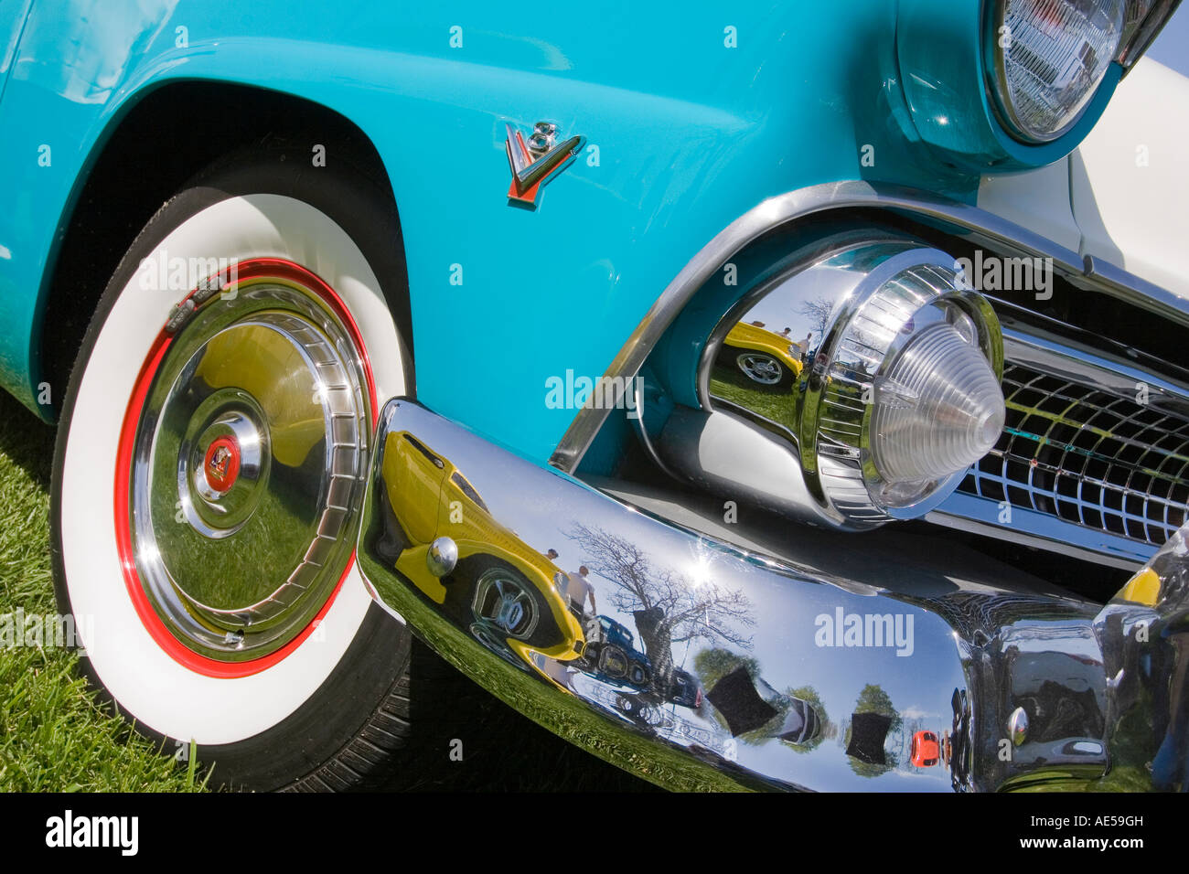Turquoise 1955 Ford Fairlane convertible classic car with front headlights grill and wheel with whitewall tire with red trim Stock Photo