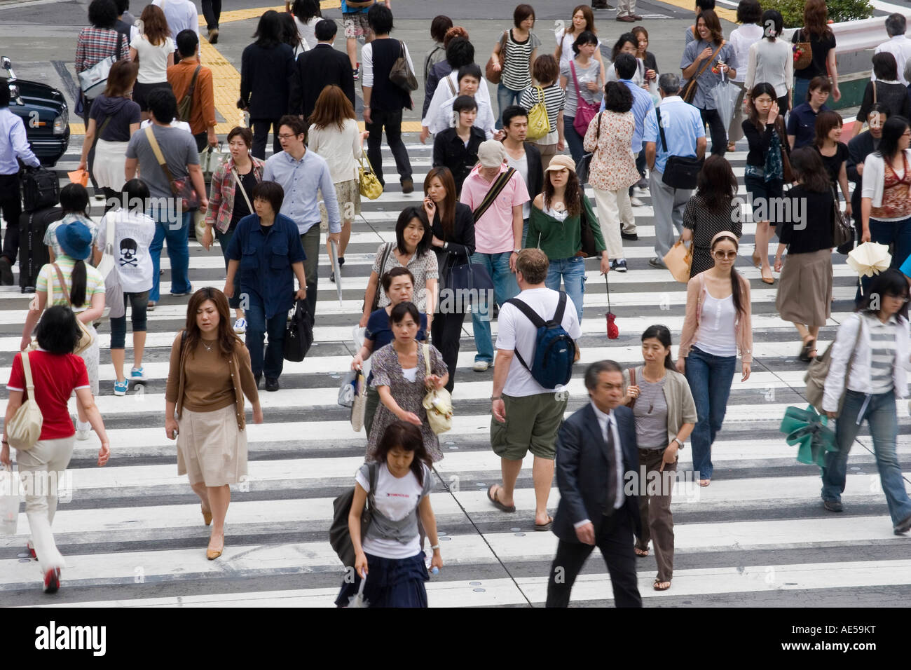 Japanese people walking across a busy street at a crosswalk in Tokyo Japan Stock Photo