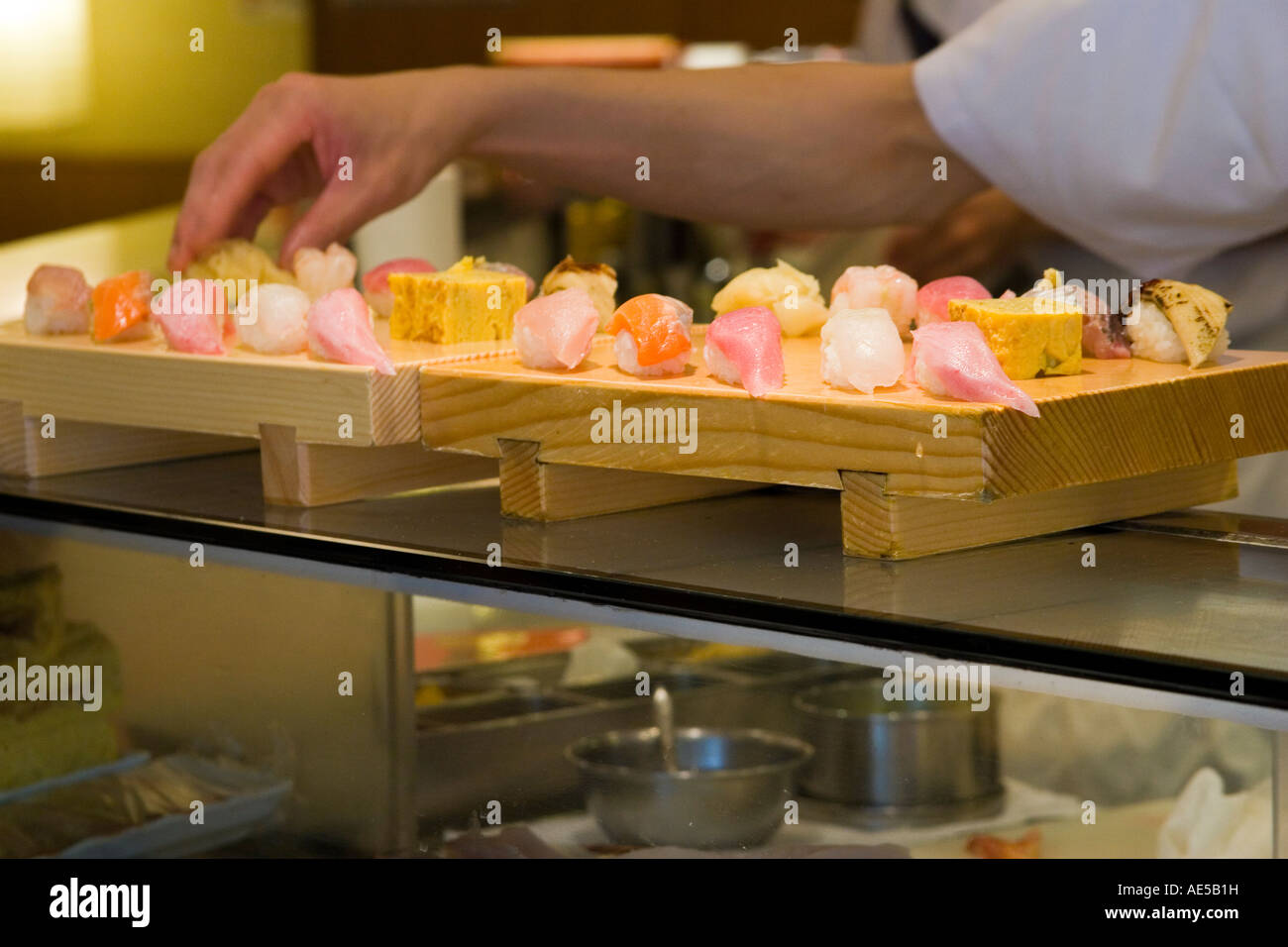 Sushi chef preparing sushi and putting them on wooden geta trays on the counter of a Japanese sushi restaurant Tokyo Japan Stock Photo