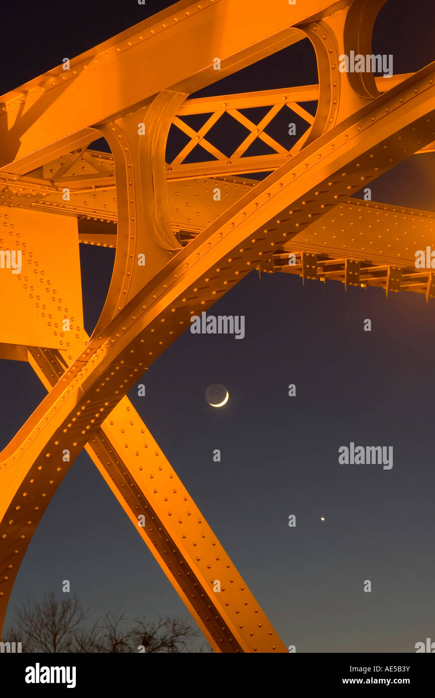 A star and a sliver of a moon shining behind metal beams of Tower Bridge at night in Sacramento California Stock Photo