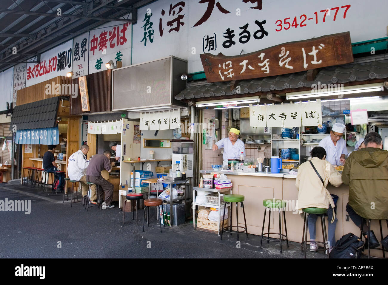Tiny restaurant stalls serving Japanese breakfast food to customers in the outer market of Tsukiji Fish Market in Tokyo Japan Stock Photo