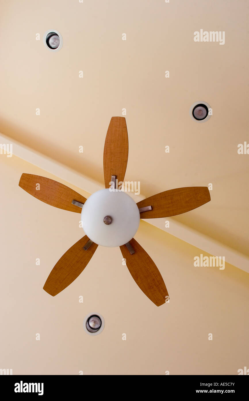 Ceiling fan with five maple wood blades mounted on ridge beam with three lights in ceiling - interior design Stock Photo