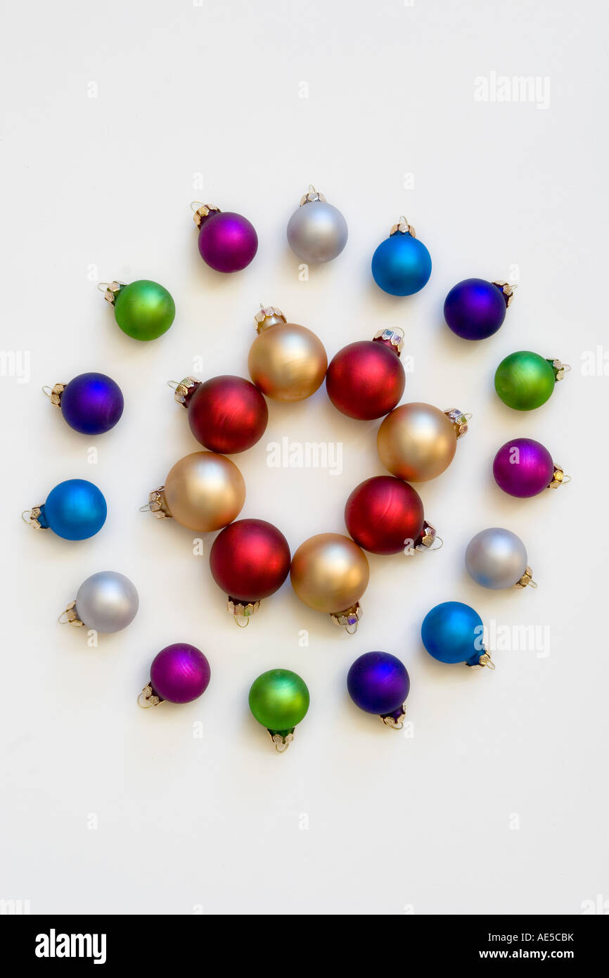 Red and gold Christmas balls in a circle surrounded by smaller multicolored holiday ornaments against a white background Stock Photo