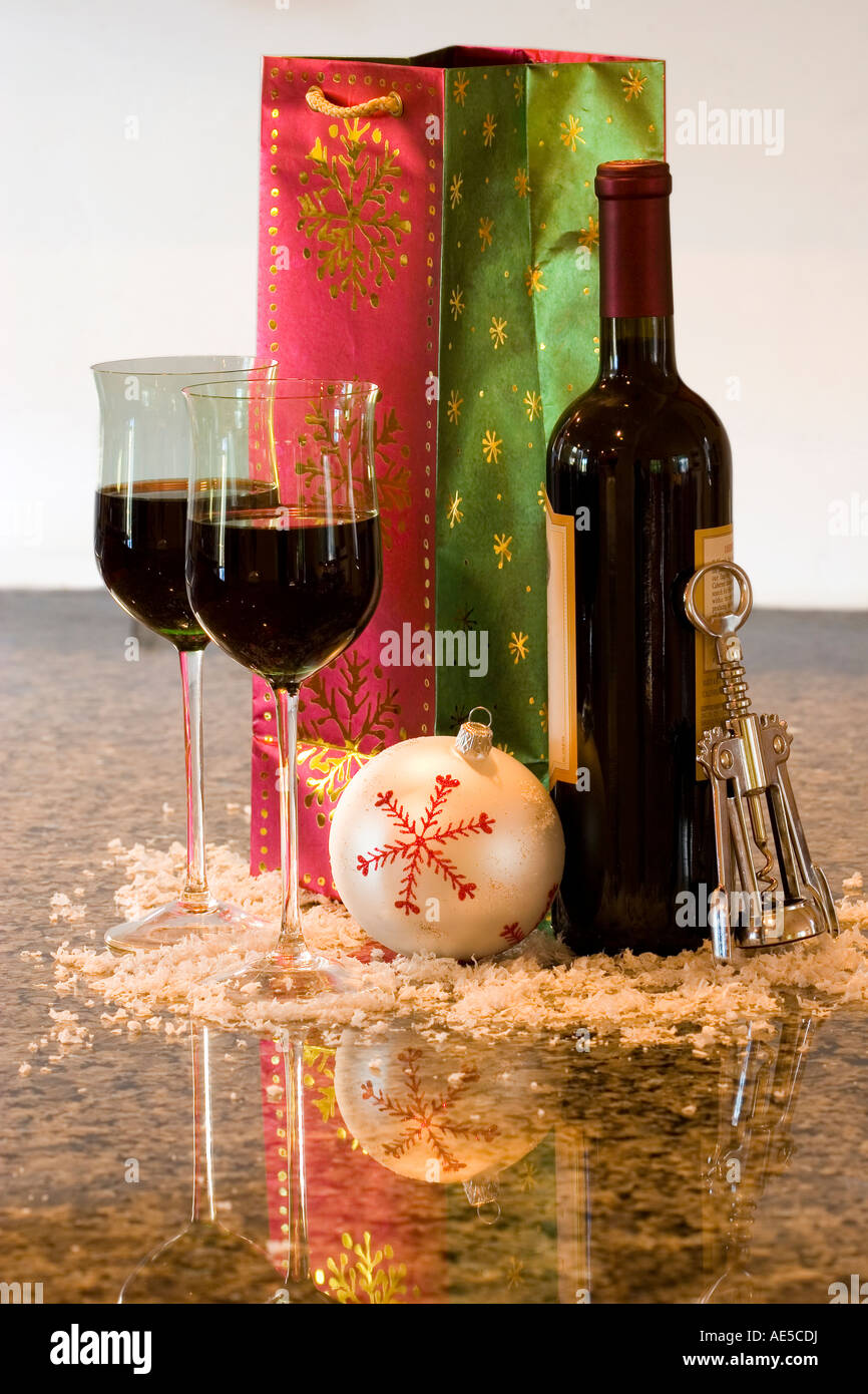 Gift of red wine bottle with two glasses next to festive Christmas ornament  and bottle opener on granite counter Stock Photo - Alamy