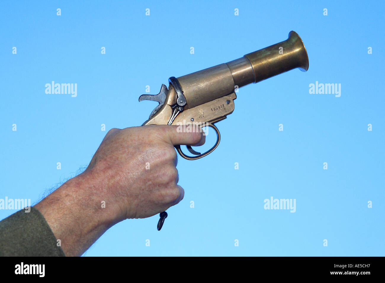 Soldier holding WW1 flare gun pointing up against the blue sky Stock Photo