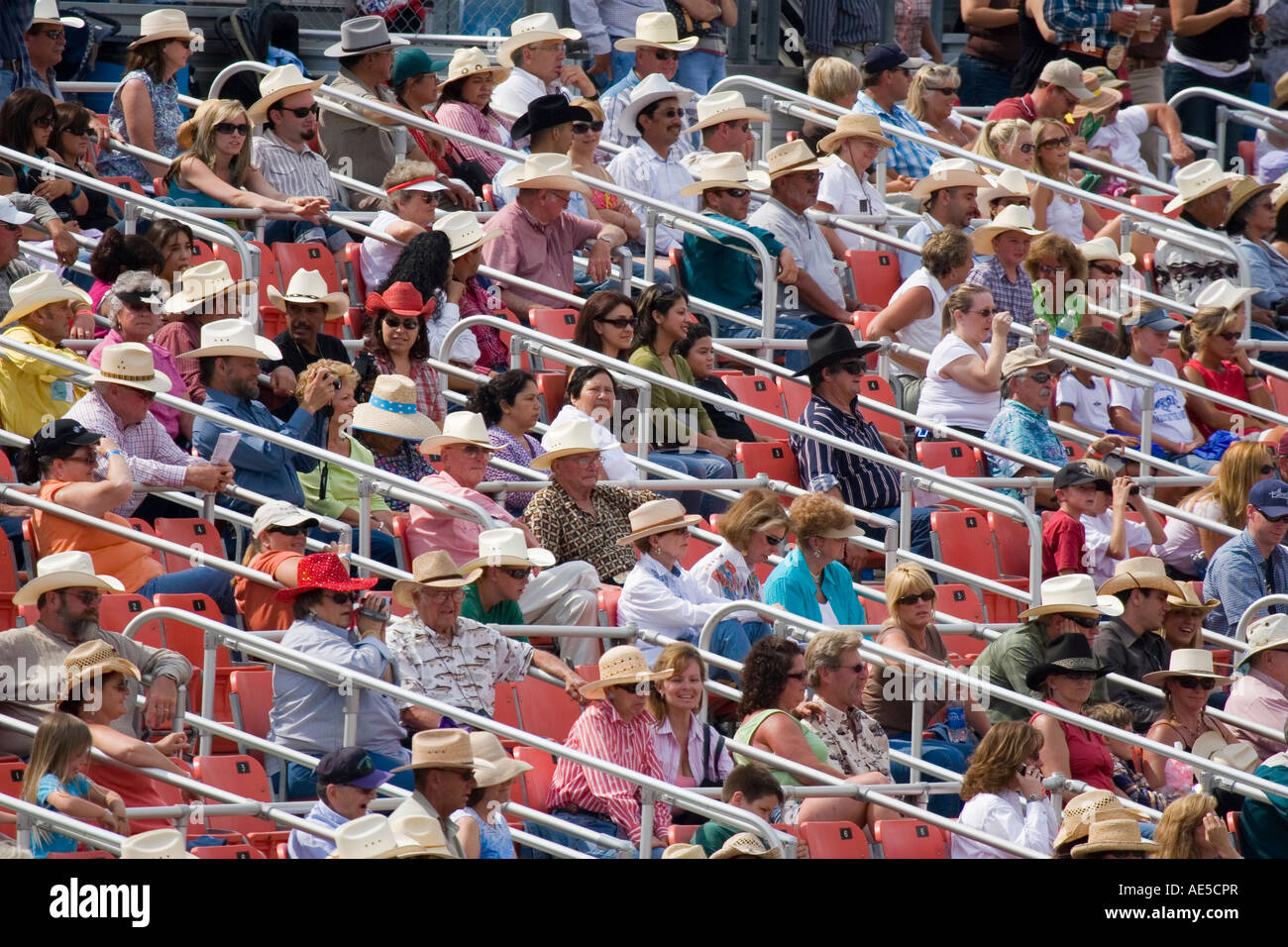 Hispanic and Caucasian crowd wearing cowboy hats watching rodeo from box seats of the stadium stands Stock Photo