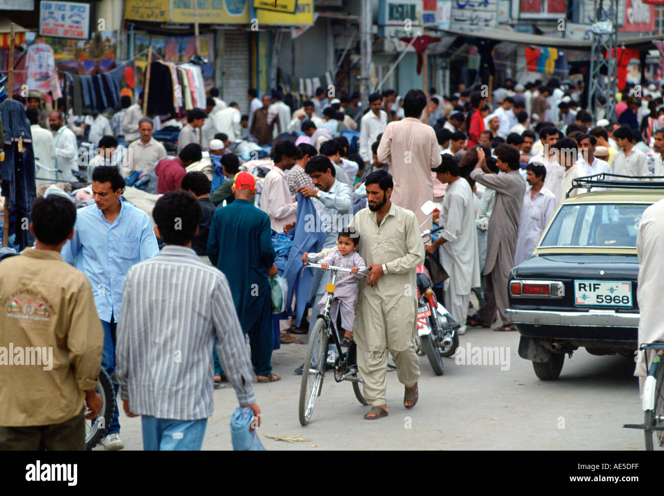 Man wheeling child on bicycle in crowded street in Islamabad in Pakistan Stock Photo