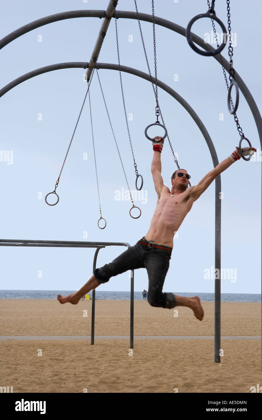 Caucasian man on the rings set swinging from one ring to the next Santa Monica Beach Los Angeles California Stock Photo