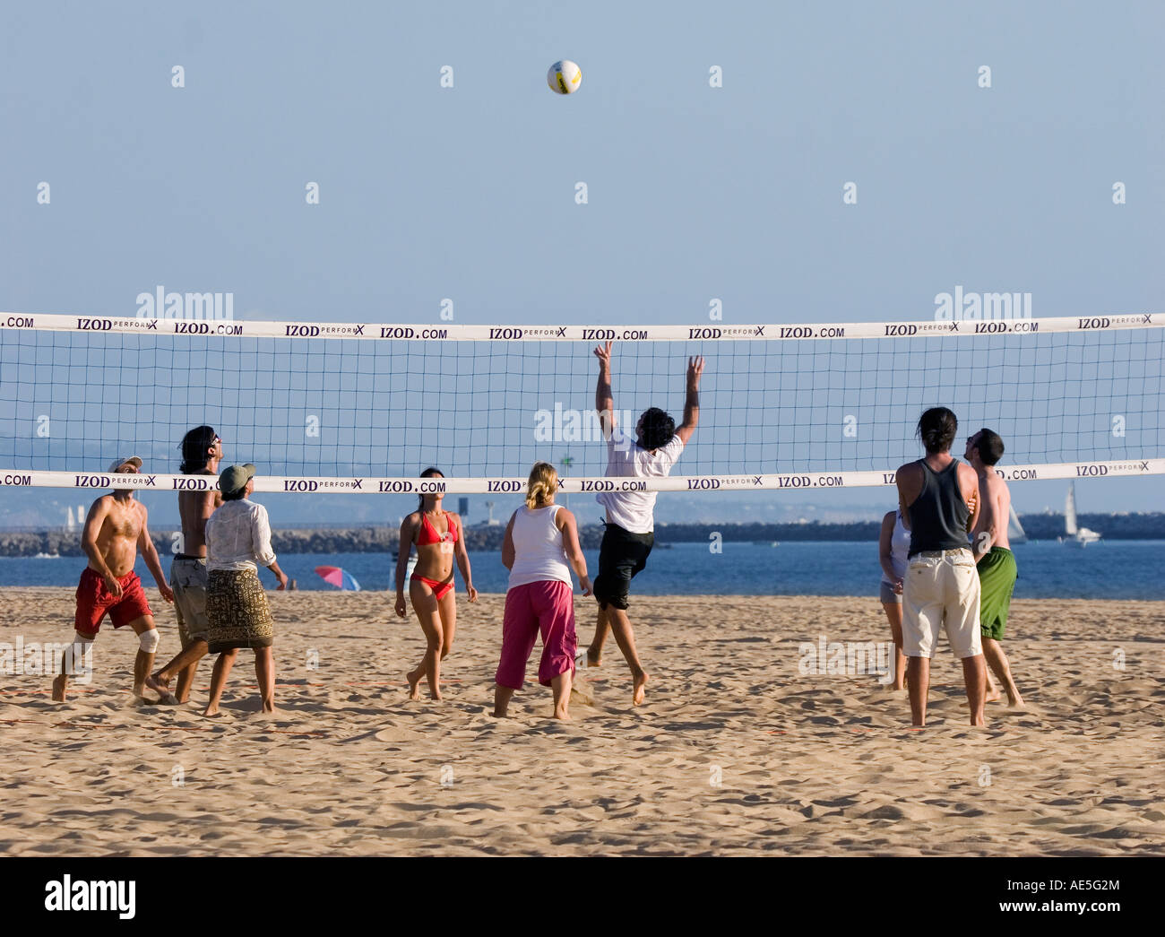 Friends playing game of beach volleyball with ball being set over net