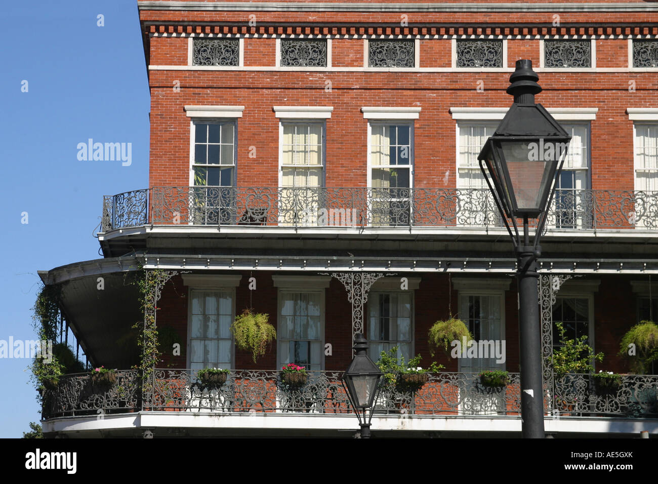 Building in classic New Orleans  architecture with ornate wrought ironwork on balcony railings with gas lamp - French Quarter Stock Photo