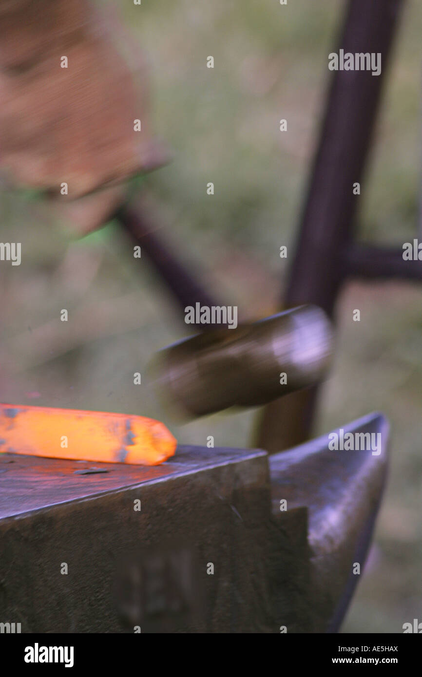 Hammer hitting a red hot piece of iron on an anvil Stock Photo Alamy