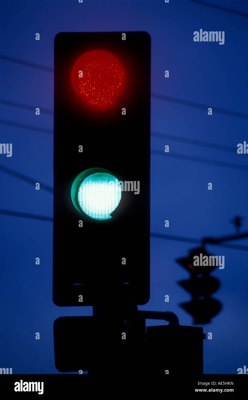Traffic light at night indicating both stop and go at the same time - Illustrates idea of mixed messages or confusion Stock Photo