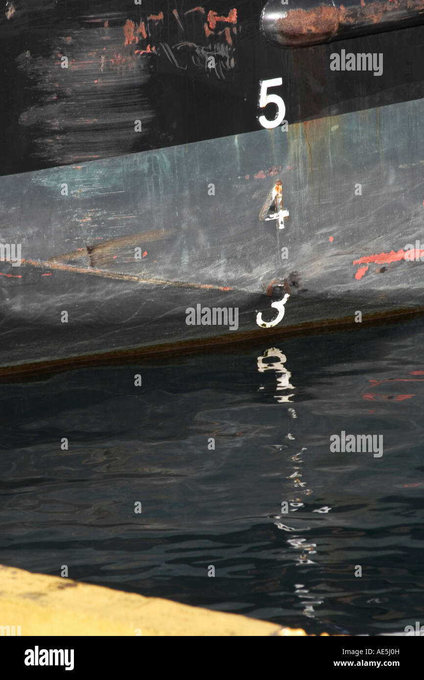 Depth measurement numbers on the side of a boat reflecting in the water