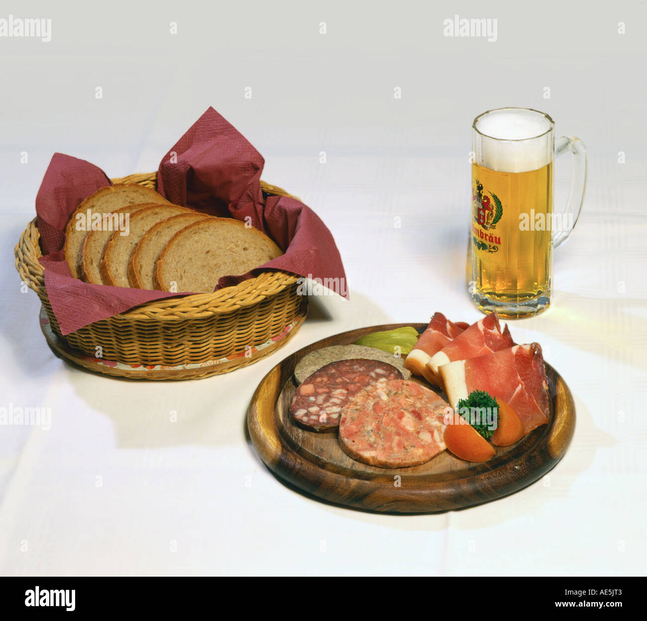 Plate with saussages and ham, basket with bread and glass of beer Stock Photo