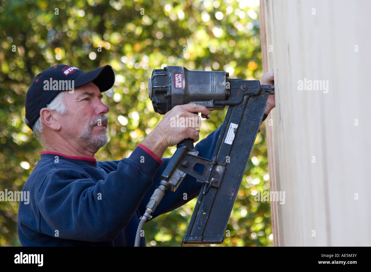 Carpenter using nail gun to secure plywood to exterior of house to Stock Photo 13576238 Alamy