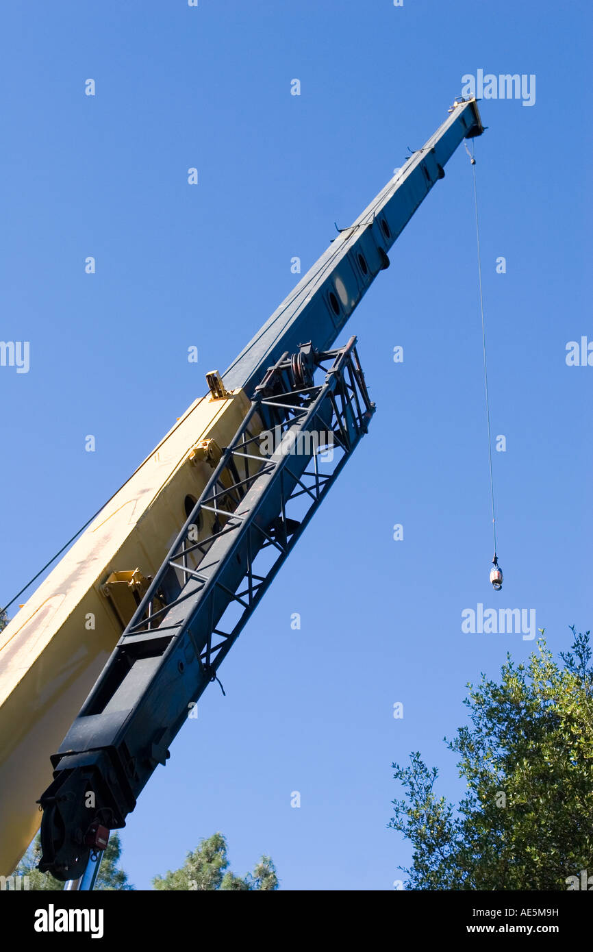 Large crane with hydraulic telescopic arm lowering the hook on a cable from the boom at a construction site Stock Photo