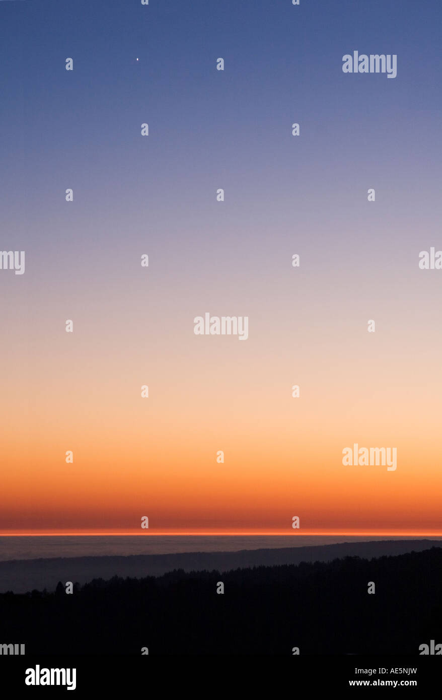 Layers of land water and sky with glowing sunset and single star in ...