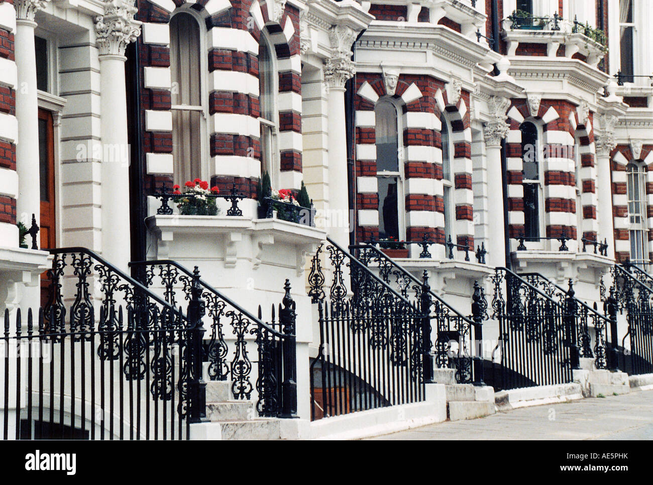 Brick and stone row houses with wrought iron banisters and flower boxes in the Kensington area of London England Stock Photo