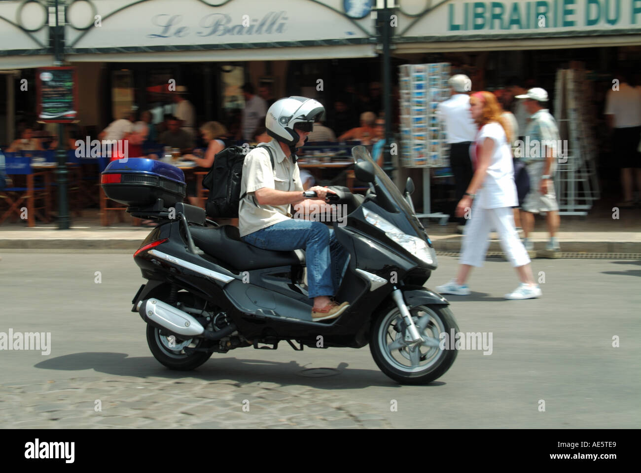 St Tropez waterfront scooter rider hot summers day driving past