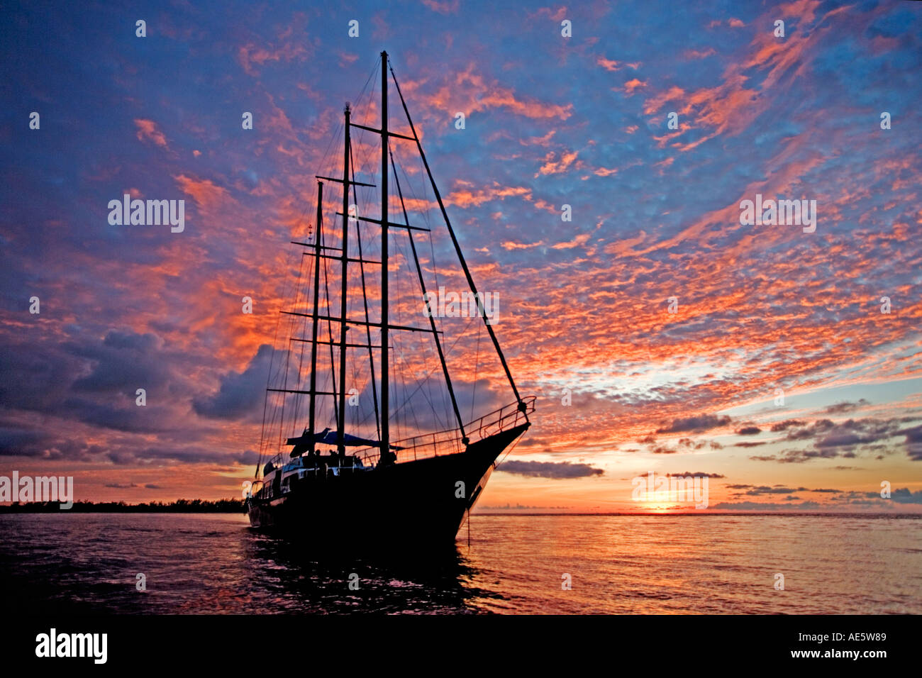 Yacht silhouetted against sunset Sea Star Sailing Yacht Property released Seychelles Stock Photo