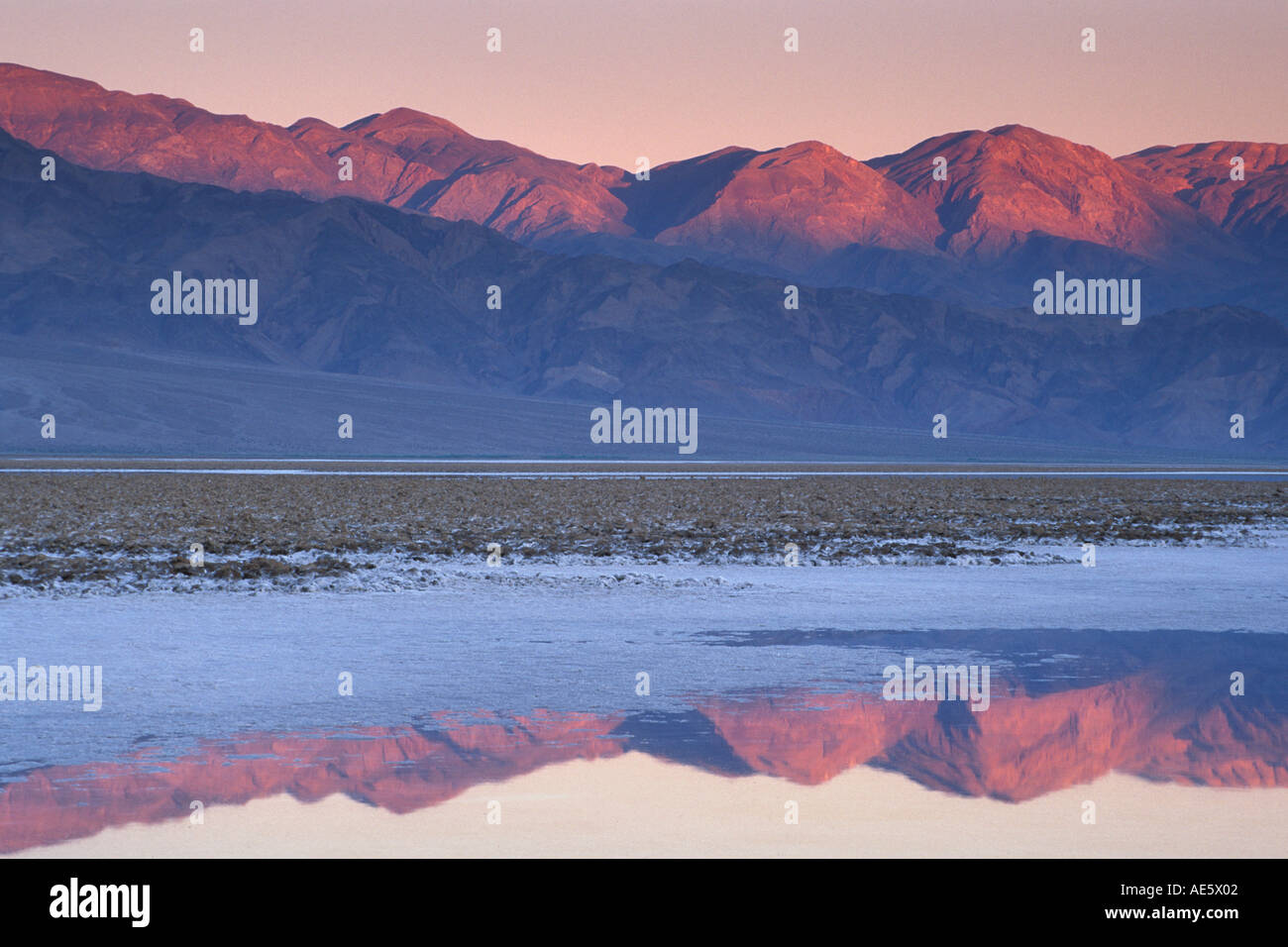 Sunrise light on Panamint Mountains over flooded salt pan Devils Golf Course Middle Basin Death Valley California Stock Photo