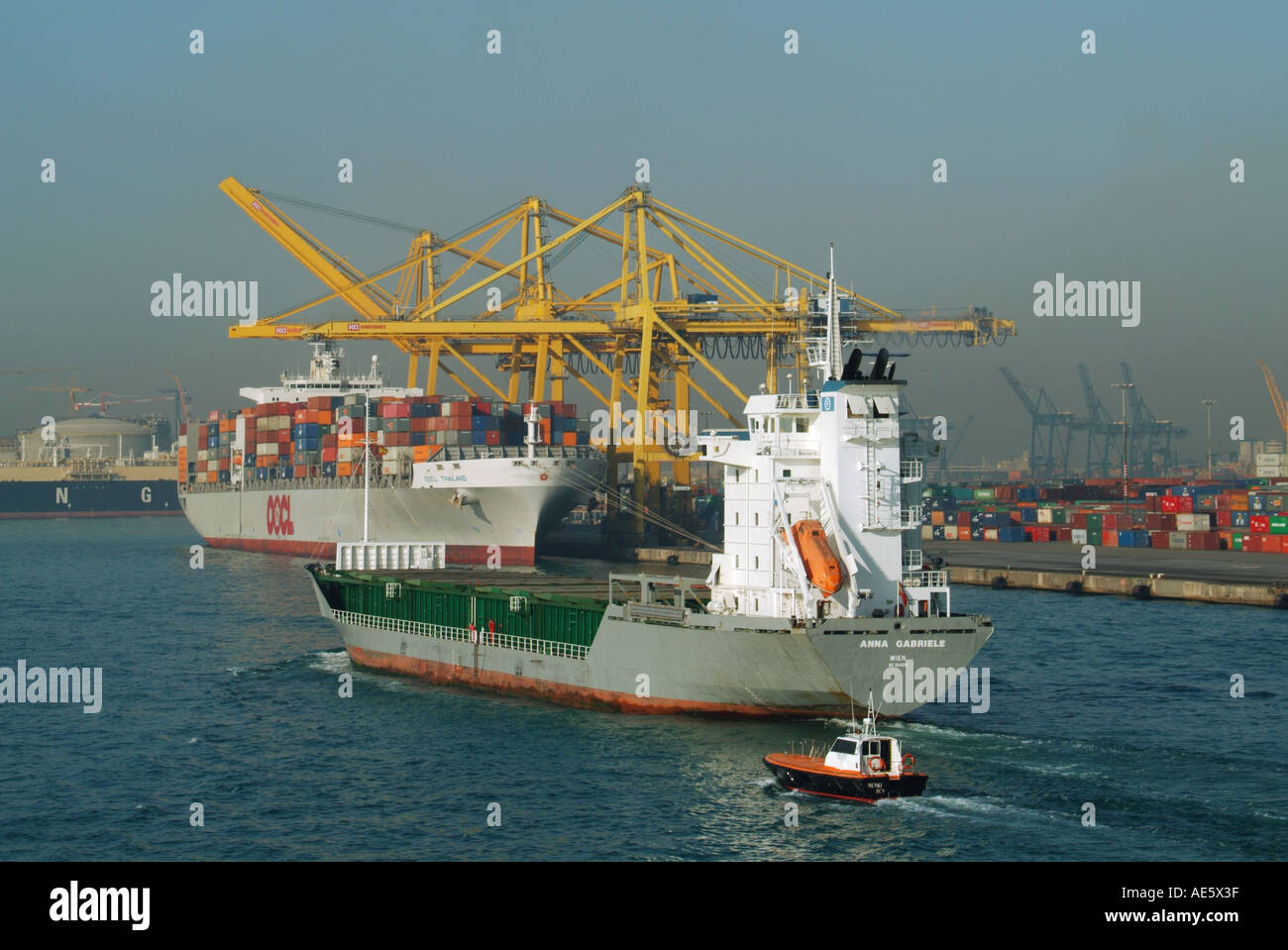 Barcelona shipping container port with dockside cranes and containers bulk carrier leaving port Stock Photo