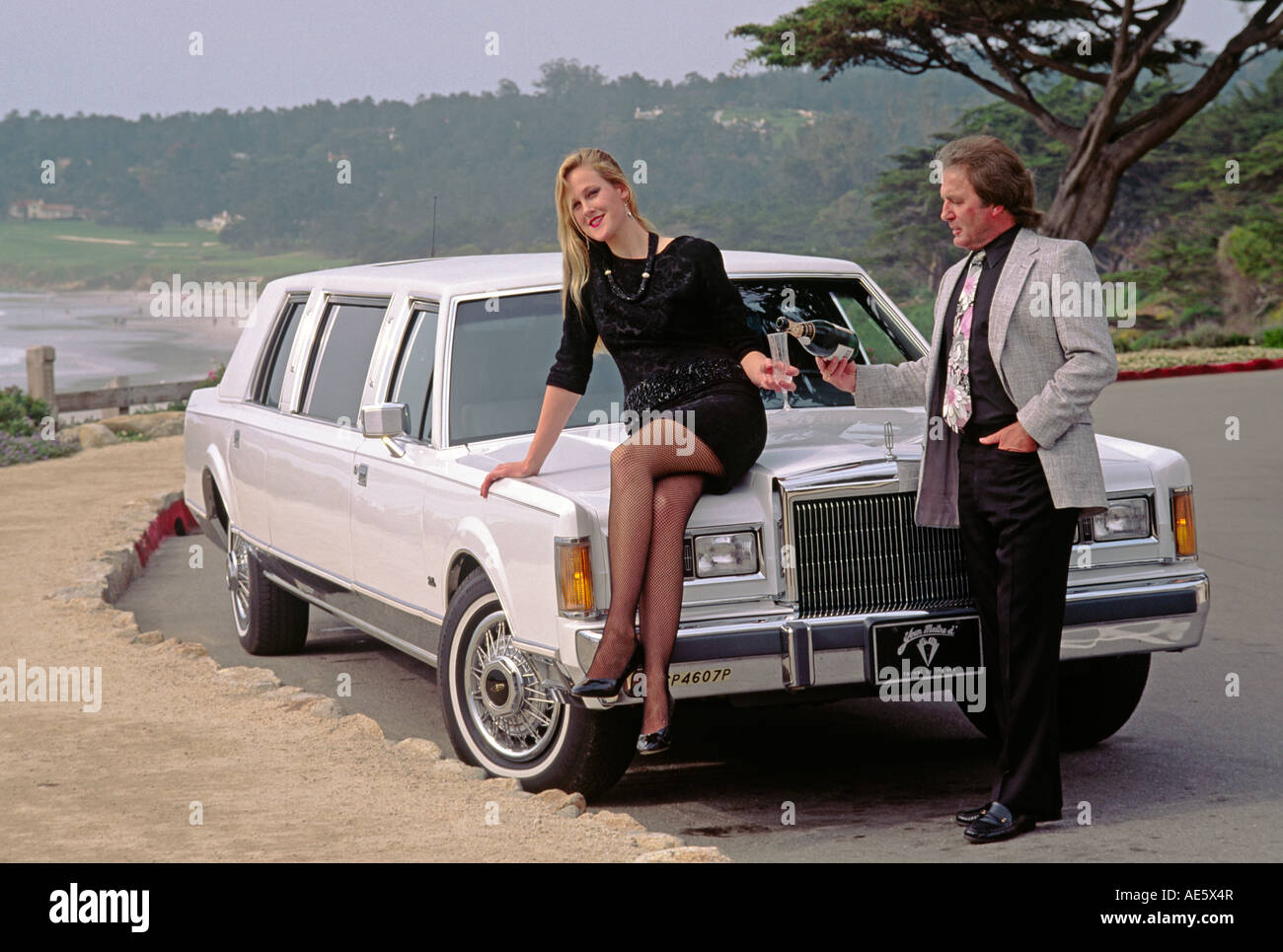 Jamie and Hans drink champagne on a white stretch limo parked on scenic drive CARMEL CALIFORNIA Stock Photo