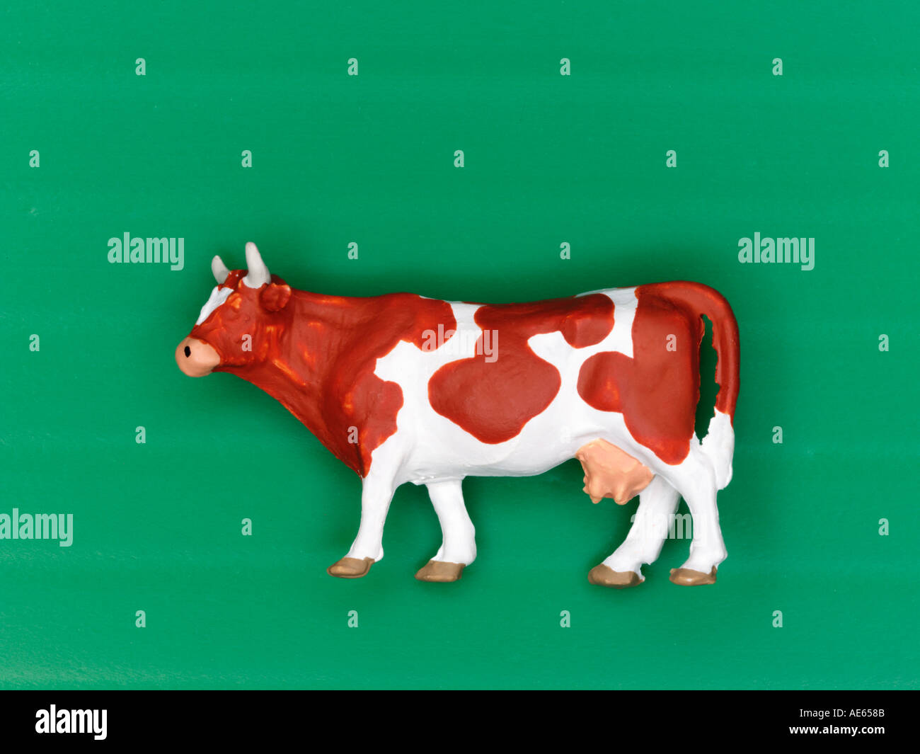 Plastic model cow on green background Stock Photo