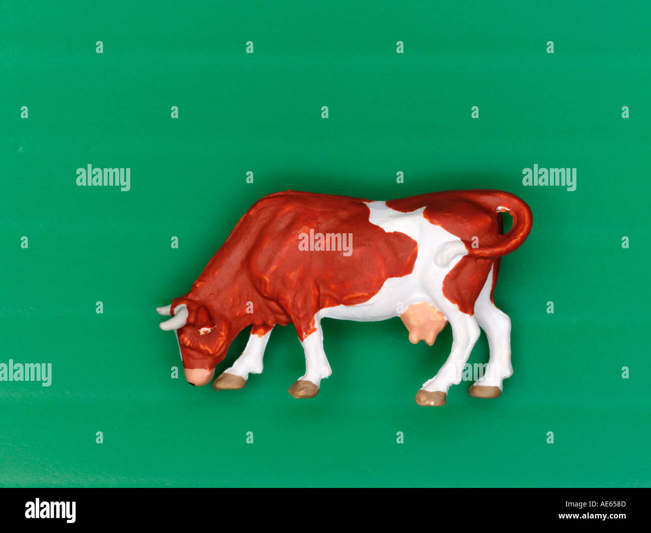 Plastic model cow grazing on a green background Stock Photo
