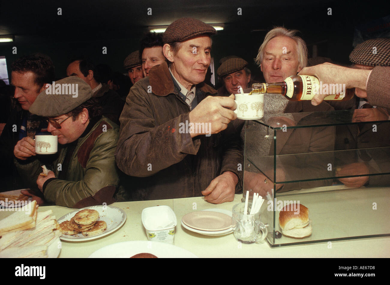 Farmers enjoy cup of tea and a splash of Bells Whisky, Farmers Christmas Market Knighton, Shropshire & Powys Wales December 1985 1980s UK HOMER SYKES Stock Photo