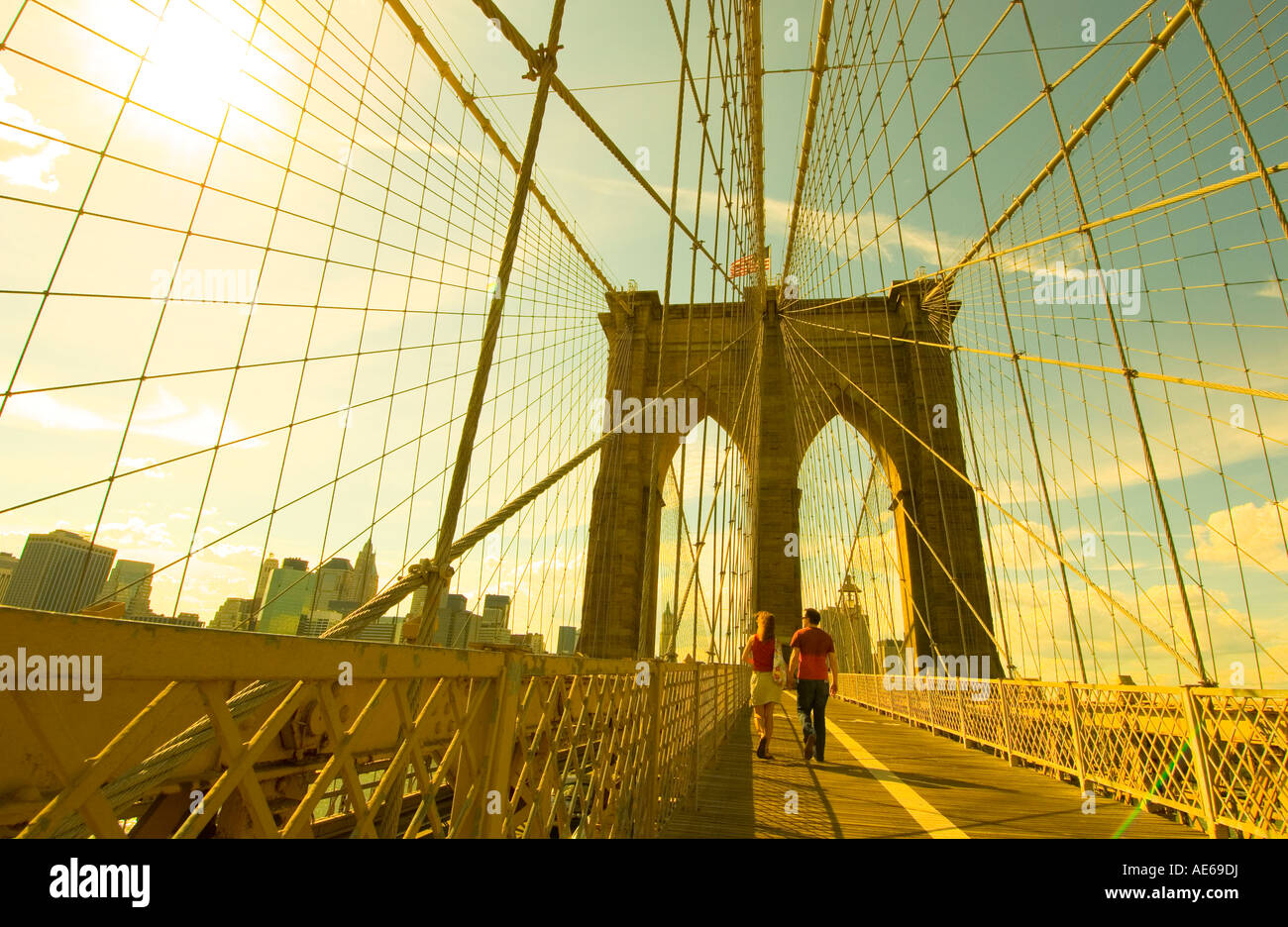 a couple crosses the Brooklyn Bridge going towards Manhattan in the ...