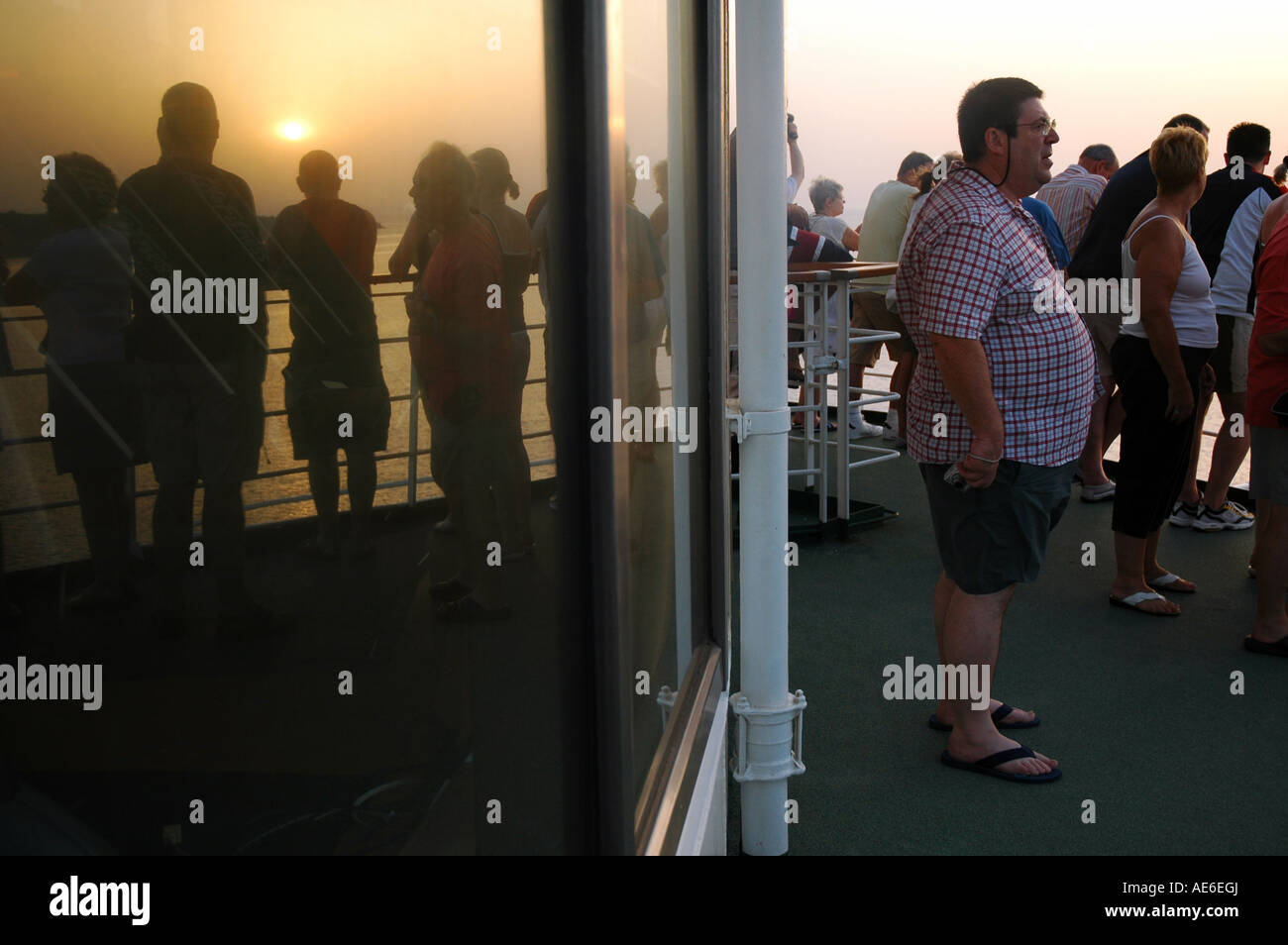 Tourists aboard a cruise ship watching the sunrise as the vessel ...