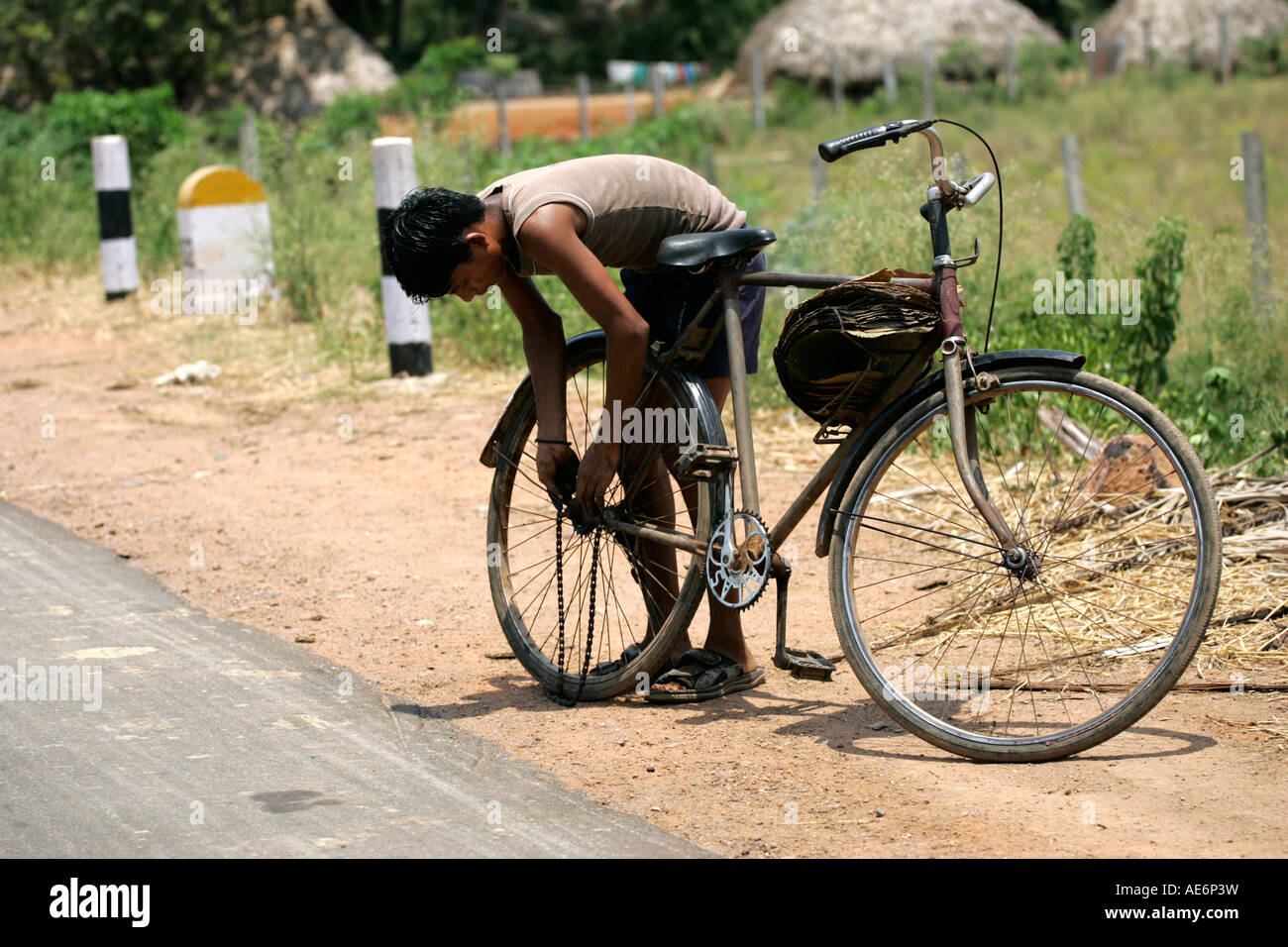 Indian boy repairs bicycle next to the road Stock Photo