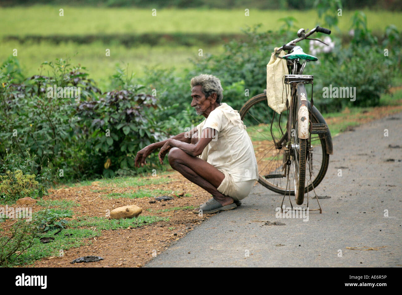 Old Indian man with bicycle resting thinking next to road Stock Photo