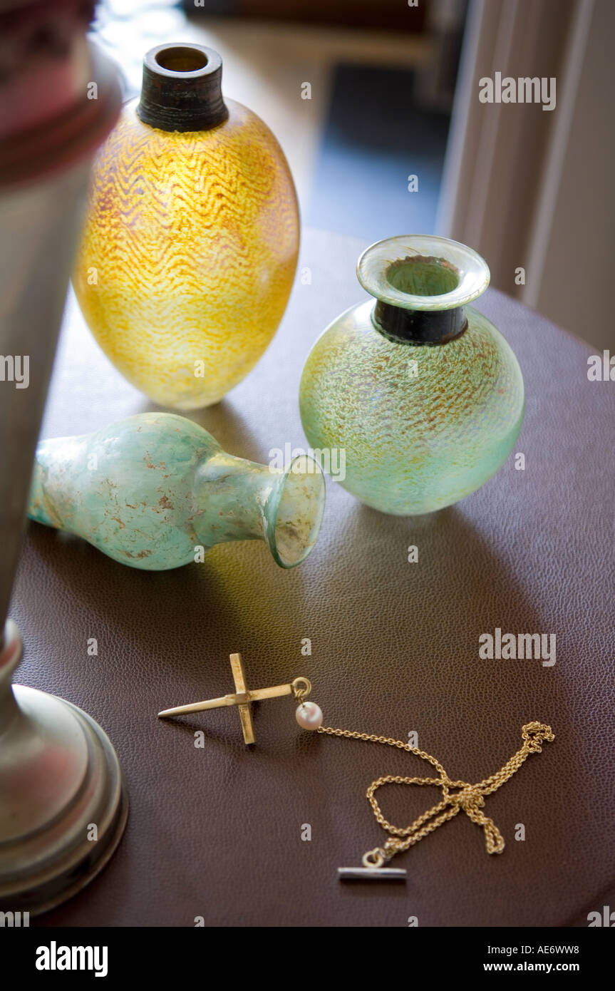 antique glass vessels and gold crucifix on a side table Stock Photo