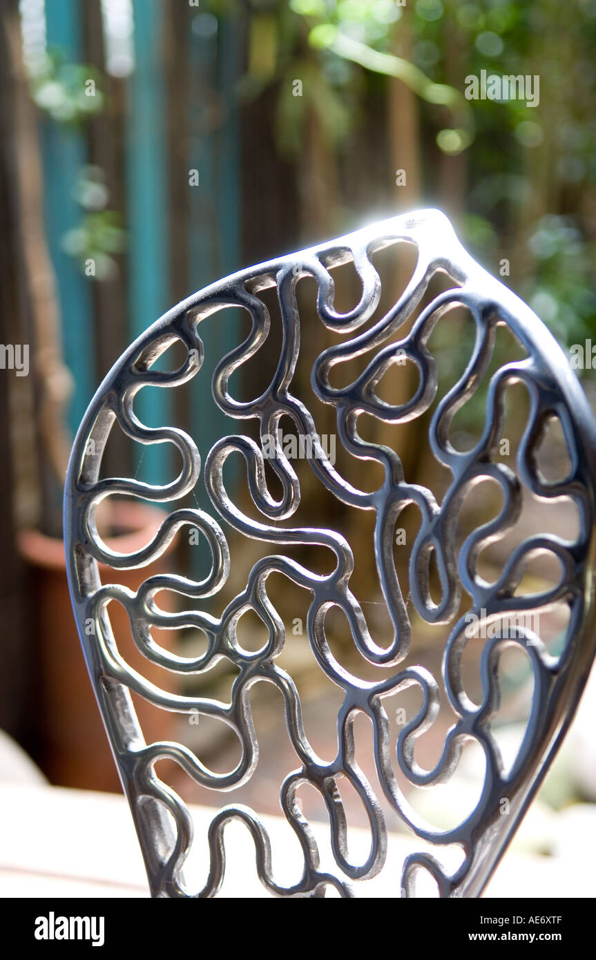 Squiggly wrought iron chair black glinting in the sun Stock Photo