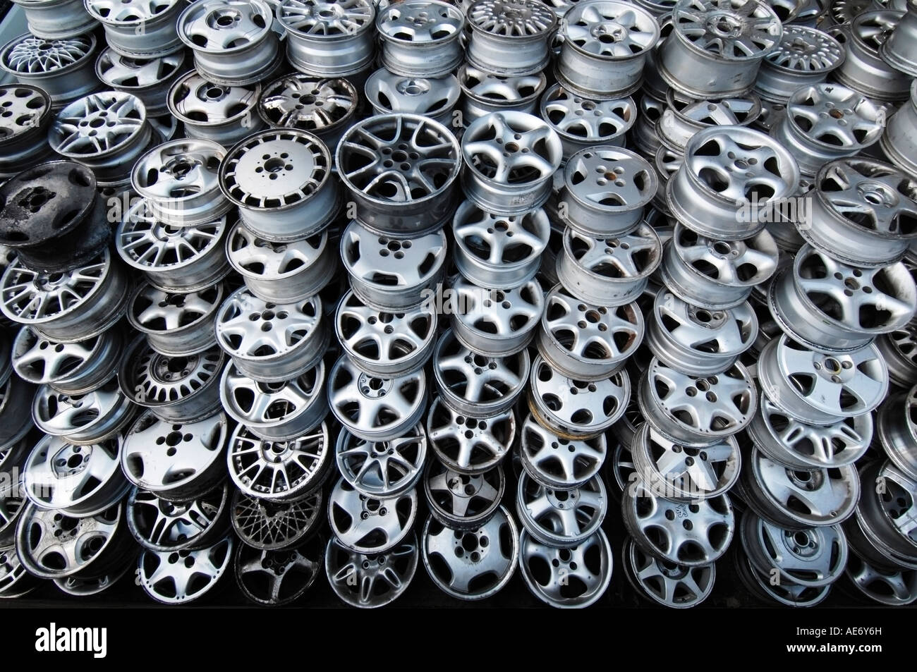 A pile of discarded second hand alloy car wheels at a scrapyard