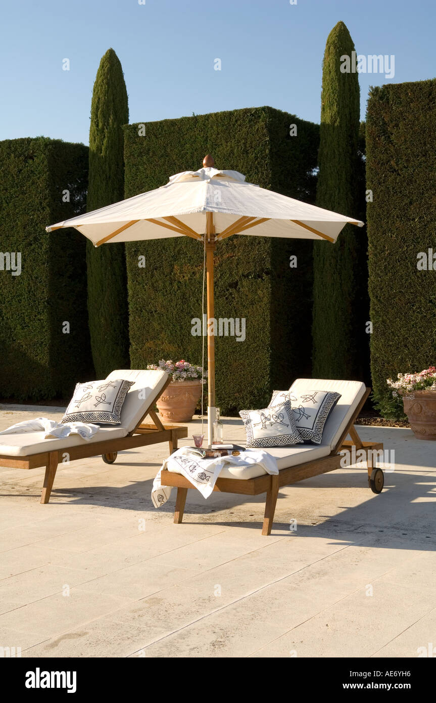 sun loungers and parasol in front of a trimmed hedge in the South of France Stock Photo