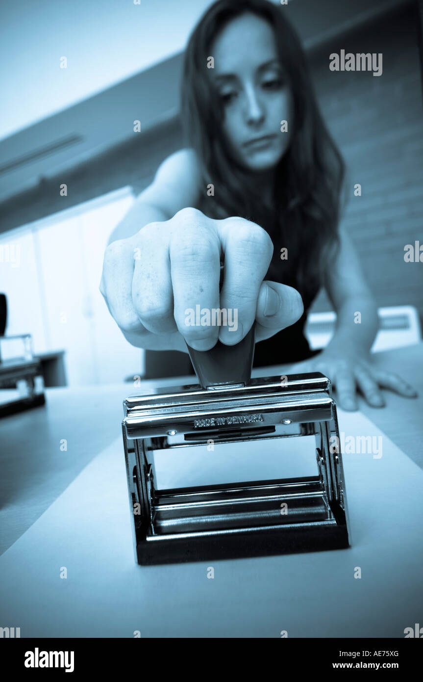 Woman in modern office stamping document using hand stamp blue toned