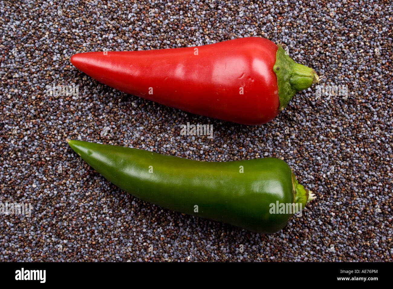 Two red and green chili peppers on blue poppy seeds Stock Photo