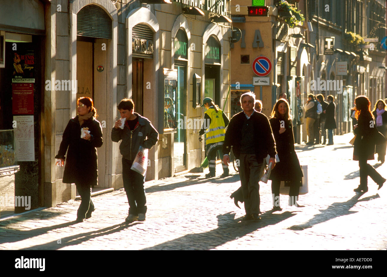 Late afternoon sun highlights pedestrians along Via Della Croce in Rome Italy  Stock Photo