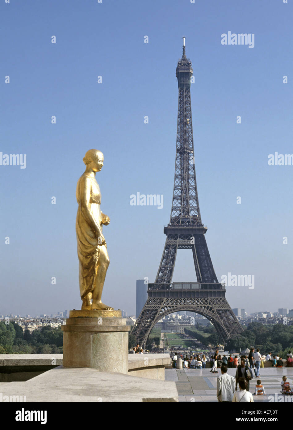 One of eight gilded gold statues at place du Trocadéro on terrace of the Rights of Man with Eiffel Tower landmark structure beyond Paris France EU Stock Photo