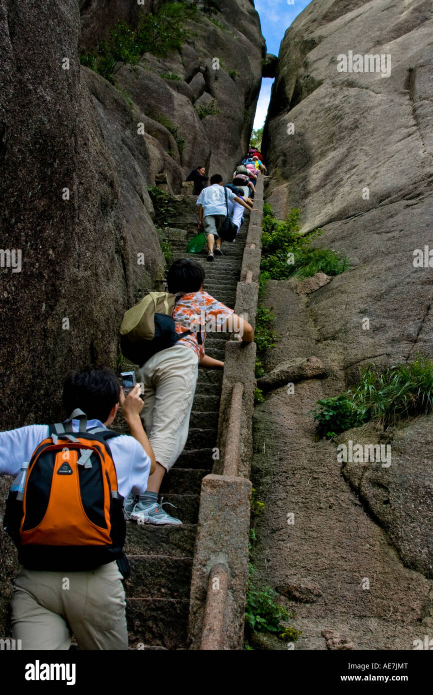Hikers Climbing Stone Stairs up Gleam of Sky toward Suspended Stone Huangshan Mountains China Stock Photo