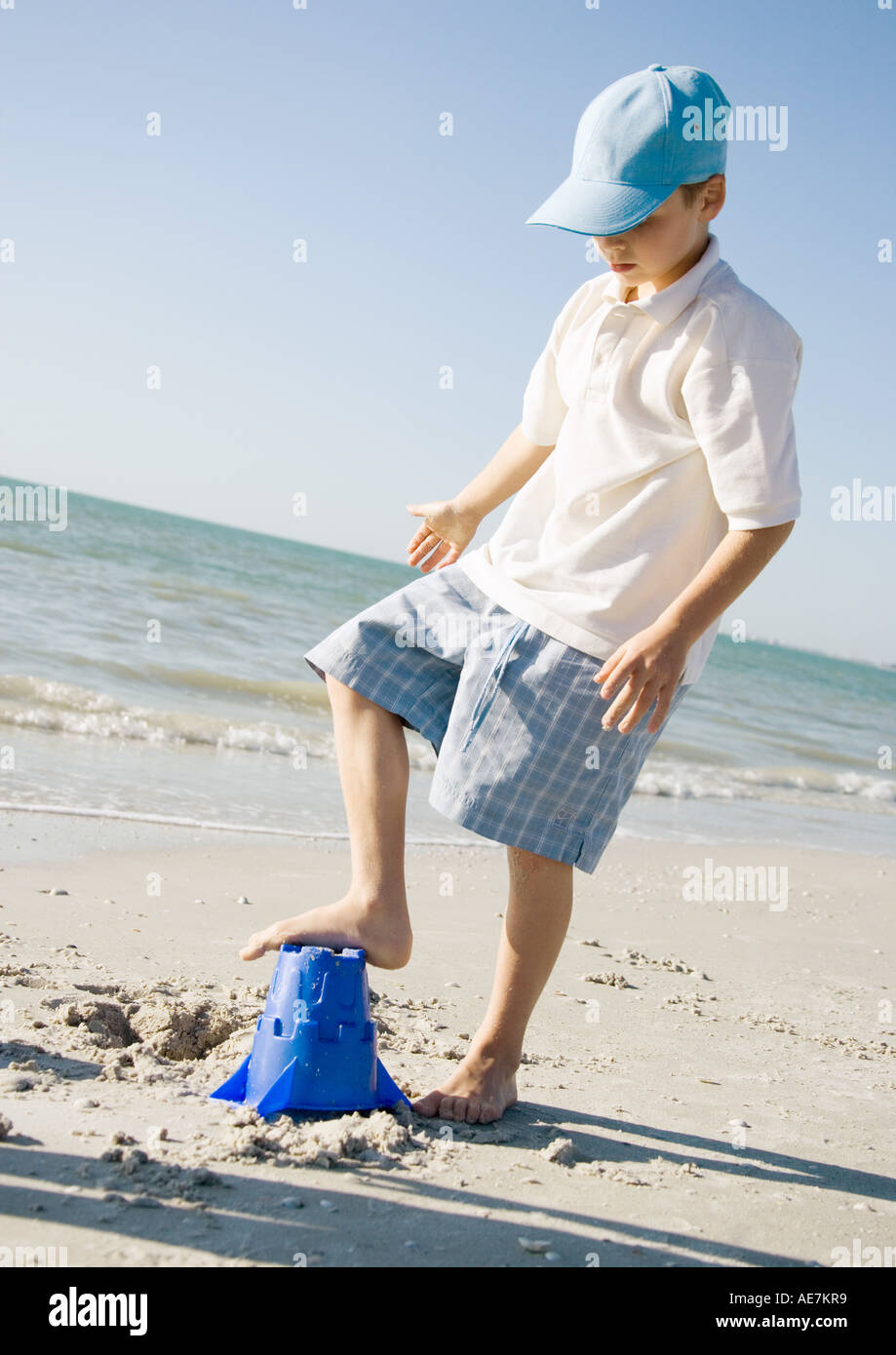 Boy stepping on sand bucket on beach Stock Photo Alamy
