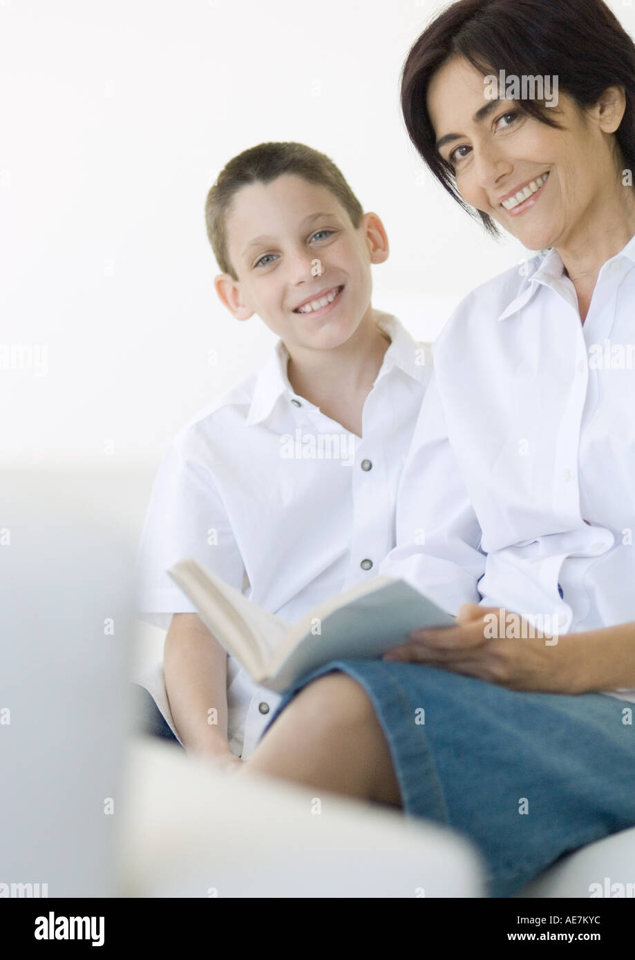 Boy and mature woman with book, smiling at camera Stock Photo